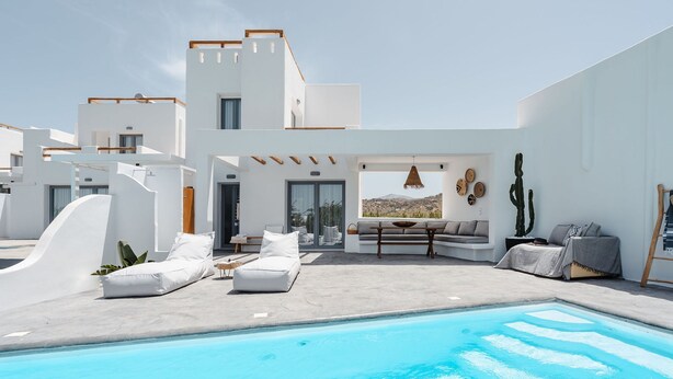 A modern outdoor pool area with white lounge chairs and a seating area with cushions. - Villa Isola Plaka Naxos (Naxos)