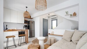 A modern kitchen with white cabinets, a wooden countertop, and a hanging light fixture. - Villa Isola Plaka Naxos (Naxos)