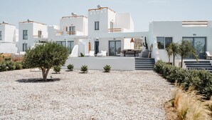 A modern, white building with multiple balconies and a gravel courtyard. - Villa Isola Plaka Naxos (Naxos)