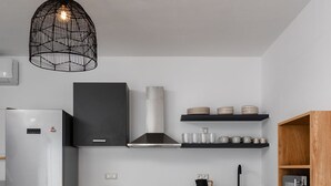 A modern kitchen with a central island, two stools, a refrigerator, a stove, and a hanging light fixture. - Villa Kaya Plaka With 3 Bedrooms and 3 Bathrooms (Naxos)