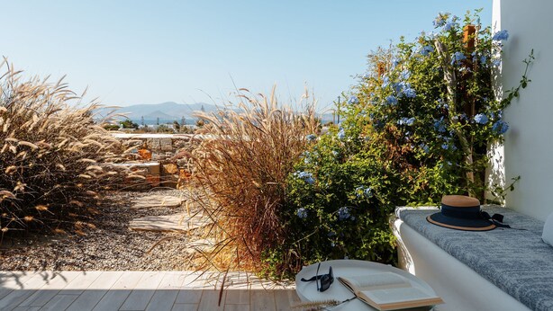 A terrace with a view of mountains, a white wall, and a table with a hat and a book. - Julie s Luxury Apartment (Naxos)