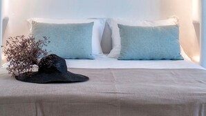 A bedroom with a curved ceiling, a bed with two pillows, a hat, and a hanging light fixture.