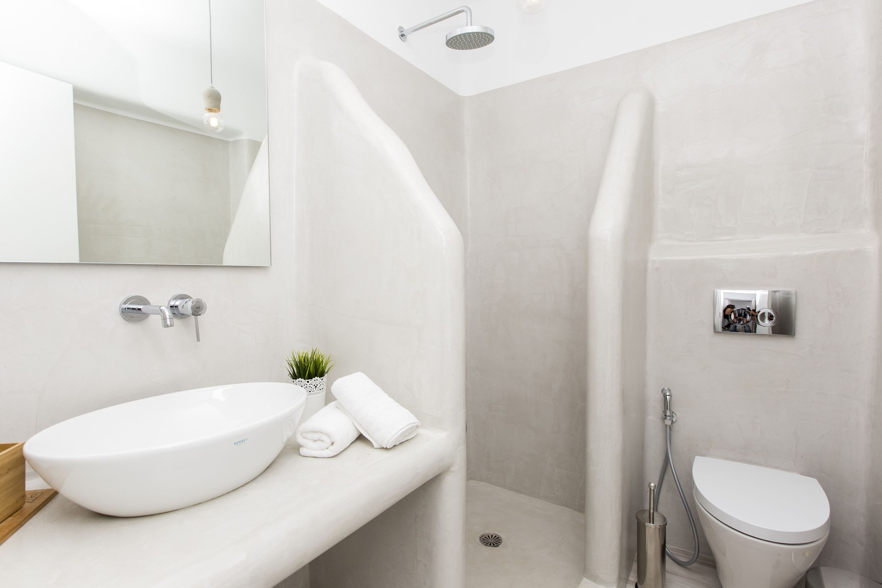 Ein modernes Badezimmer mit einem weißen Waschbecken, einer Toilette und einer Duschkabine.