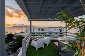A rooftop terrace with a view of the sea, white furniture, and a hot tub.