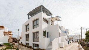 A modern white building with a flat roof, large windows, and a staircase leading to the entrance. - Yara sea View Apartment Agia Anna (Naxos)