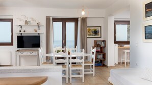 A modern room with a dining area, a TV, and a bed.