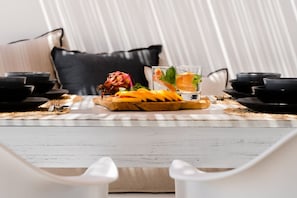 A dining table with a fruit platter, two glasses of water, and black bowls.