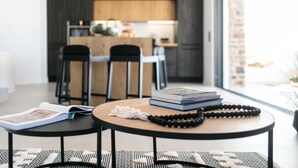 A modern dining area with a round table, two chairs, and a view of a kitchen in the background. - Villa Anamnisis With 5 Bedrooms and 5 5 Bathrooms (Naxos)
