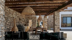 An outdoor patio with stone walls, wooden furniture, and a thatched ceiling. - Villa Anamnisis With 5 Bedrooms and 5 5 Bathrooms (Naxos)
