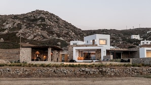 A modern house with a stone facade, a large open patio, and a view of a mountainous landscape. - Villa Anamnisis With 5 Bedrooms and 5 5 Bathrooms (Naxos)