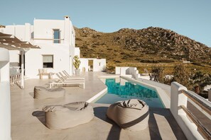 A rooftop pool area with white architecture, lounge chairs, and a view of a mountainous landscape. - 291424 - Villa Flo in Naxos (Naxos)