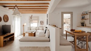 Un salon moderne avec un canapé, un téléviseur et des poutres en bois au plafond.