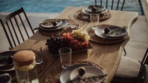 A dining table set with plates, glasses, and a fruit bowl, near a pool. - Villa Andalusia With 4 Bedrooms and 3 5 Bathrooms (Naxos)