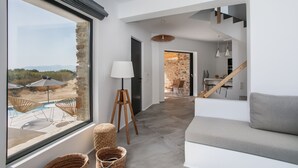 A modern living room with a large window, a sofa, wicker baskets, and a lamp. - Villa Andalusia With 4 Bedrooms and 3 5 Bathrooms (Naxos)