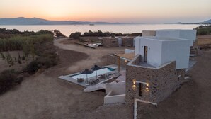 A modern villa with a swimming pool, outdoor seating, and a view of the sea at sunset. - Villa Andalusia With 4 Bedrooms and 3 5 Bathrooms (Naxos)
