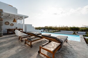 A modern outdoor pool area with lounge chairs and a dining setup. - Maison Solea Plaka With 3 Bedrooms and 3 Bathrooms (Naxos)