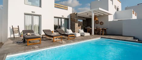 A modern pool area with lounge chairs and a stone wall.