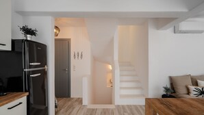 Una cocina moderna con un refrigerador negro, encimera de madera y una escalera que lleva a una sala de estar con sofá y cojines.
