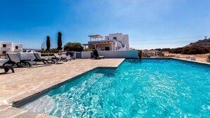 Une piscine avec des chaises longues et un bâtiment moderne en arrière-plan.