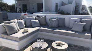 A modern outdoor seating area with a sectional sofa, two round tables with drinks, and a starfish decoration. - 293102 - Casa Magnifica (Naxos)