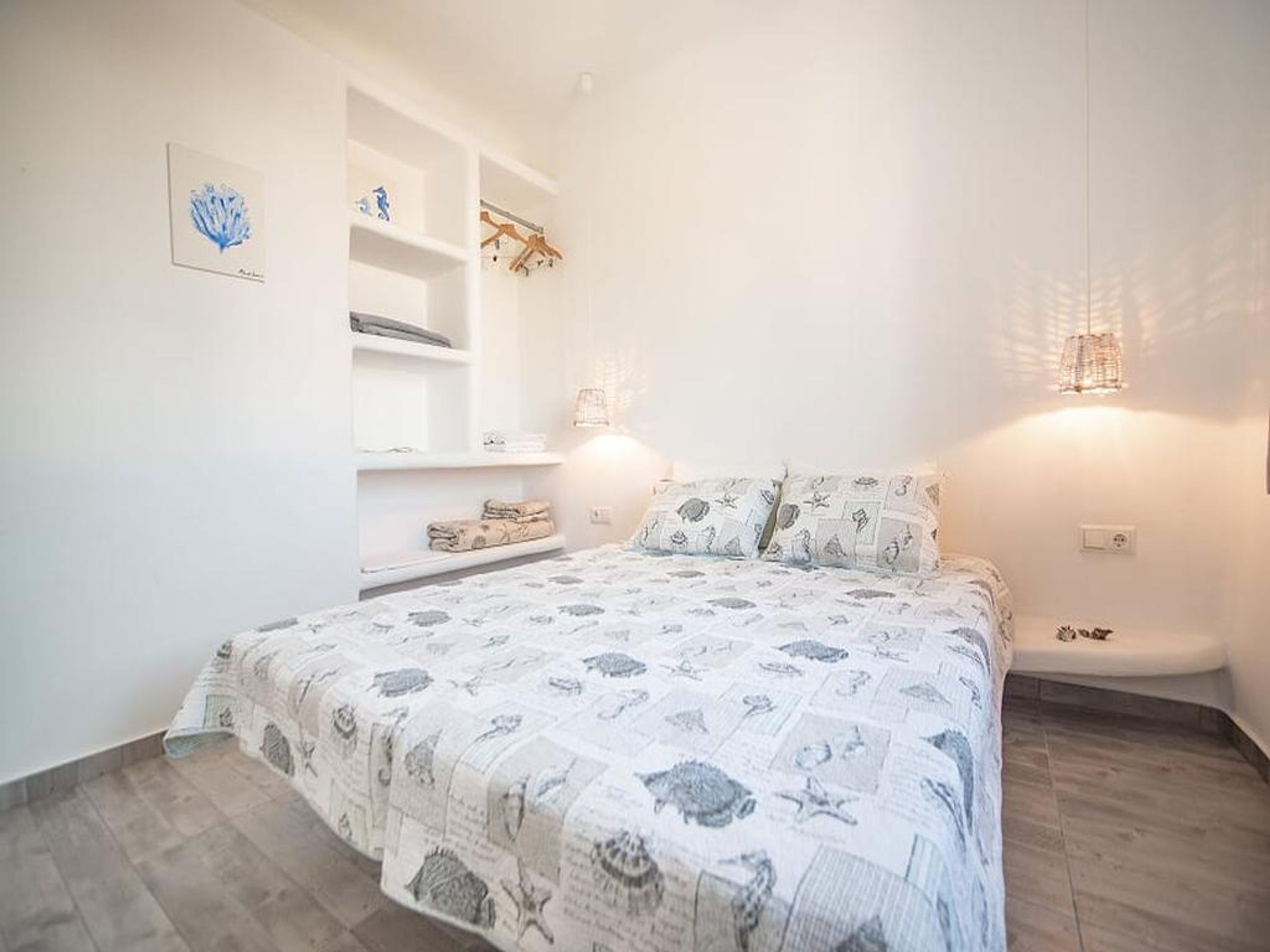 A bedroom with a bed, built-in shelving, and wall-mounted lights.