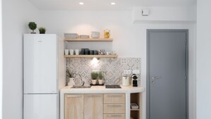 A compact kitchen with a built-in refrigerator, wooden cabinets, a sink, and a grey door. - Anamnesia Collection 2BR Apart Naxos Town (Naxos)