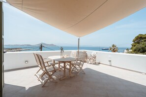 A terrace with a table and chairs, a view of the sea, and a mountain in the distance. - Kastro Suite in Naxos-chora (Naxos)