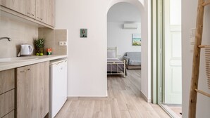 A modern kitchen with wooden cabinets, a dishwasher, and a countertop with a kettle and pineapple. - Kastro Suite in Naxos-chora (Naxos)