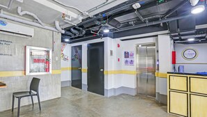 A modern interior with a reception desk, a chair, a door, and a wall-mounted sign. - MyTown Madrid, Classy Hostel Bunkbeds Makati Metro Manila (Taguig)