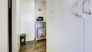 A hotel room with a microwave, a small refrigerator, and a trash bin. - MyTown Madrid, Classy Hostel Bunkbeds Makati Metro Manila (Taguig)