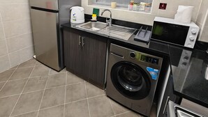 A compact kitchen with a refrigerator, washing machine, microwave, and sink. - Chic 1-bedroom apartment in enchanting Dubai with WiFi, fitness room (Dubai)