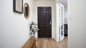 A hallway with a dark wooden door, a welcome sign, a mirror, and a bench. - Fully-equipped home for the family (Boerne)