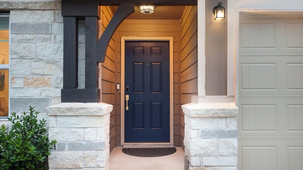 A dark blue front door with a stone base, flanked by two stone pillars, and a light fixture above. - Fully-equipped home for the family (Boerne)
