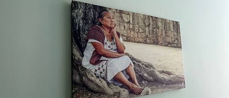 A painting of a person sitting on a rock against a stone wall.