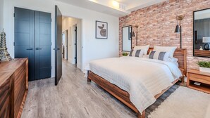 Ein Schlafzimmer mit Backsteinwand, einem hölzernen Bett, einem Nachttisch und einem Spiegel.