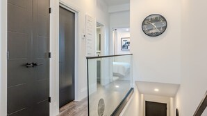 Ein modernes Interieur mit Treppe, Glasgeländer und Wanduhr.