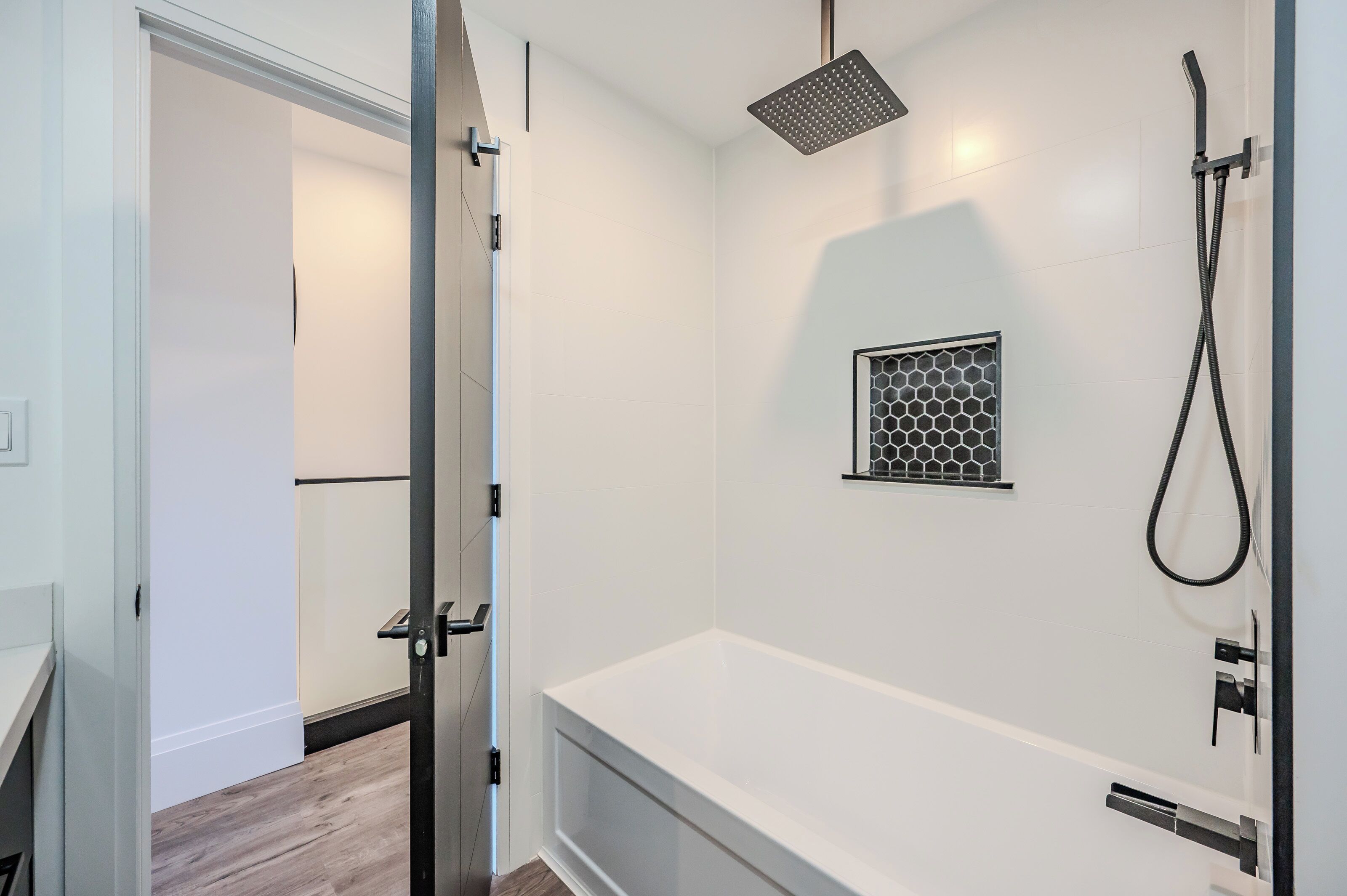 Un baño moderno con una bañera blanca, un cabezal de ducha y una unidad de ventilación pequeña en la pared.