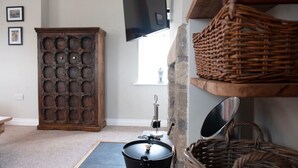 A room with a stone wall, a wooden cabinet, a black bucket, and wicker baskets. - Relaxing rural retreat (Sedbergh)
