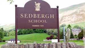 A sign for Sedbergh School with a crest, stating it was founded in 1525. - Relaxing rural retreat (Sedbergh)
