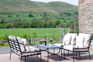 A terrace with two chairs and a table, overlooking a green valley with sheep. - Relaxing rural retreat (Sedbergh)