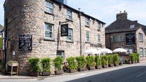 A stone building with multiple signs indicating it houses a restaurant, a country inn, and a hotel bar. - Relaxing rural retreat (Sedbergh)