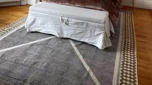 Makuuhuone, jossa on sänky, kaksi yöpöytälamppua, ikkuna ja kuviollinen matto.