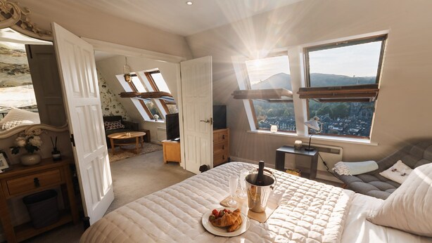 A bedroom with a large bed, a dining table with a bottle and glasses, and a view of the city through skylights. - Ambleside View Ambleside, perfect for a romantic break surrounded by breath taking scenery (Ambleside)