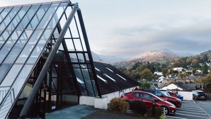 A modern building with a glass facade and a parking lot with several cars. - Ambleside View Ambleside, perfect for a romantic break surrounded by breath taking scenery (Ambleside)