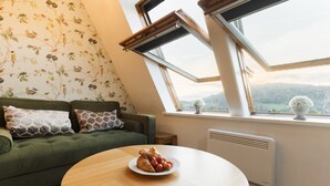 A cozy room with a green sofa, a round wooden table with a plate of croissants and strawberries, and a view of hills through skylights. - Ambleside View Ambleside, perfect for a romantic break surrounded by breath taking scenery (Ambleside)