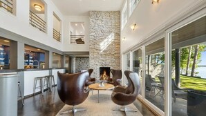 Een moderne keuken met een wand van steen, een open haard en een eethoek met lederen stoelen.