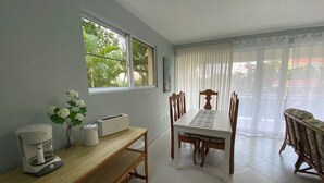 A dining area with a wooden table and chairs, a coffee machine, and a window with a view of greenery. - Oceanview 5 BR w private pool, rooftop terrace & full staff 4 min from the beach (Cofresi)