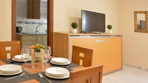A compact hotel room with a dining area, a kitchenette, a flat-screen TV, and a small potted plant. - casapatiolaspalmeras (Córdoba)