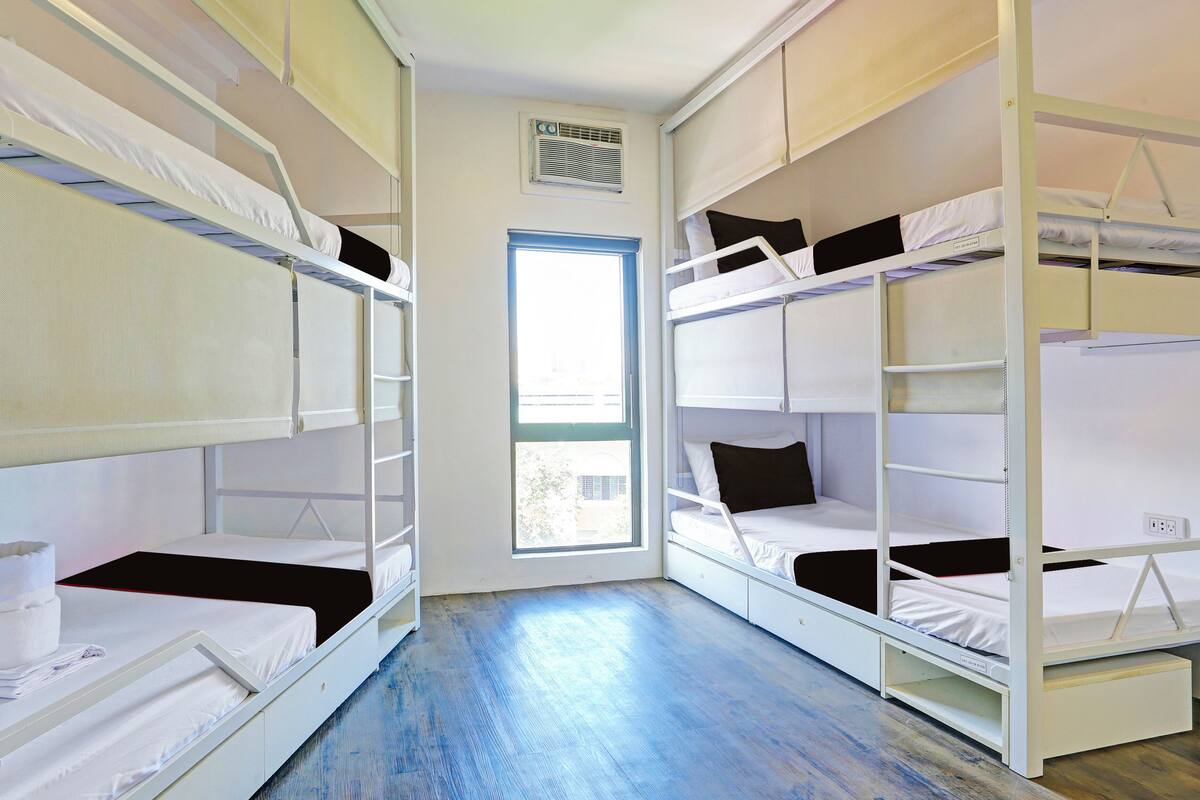 Una habitación con literas, una ventana y un equipo de aire acondicionado blanco.