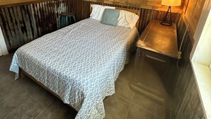Une chambre à coucher avec un lit, une table de chevet, une lampe et un tableau au mur.